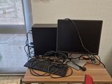 a desk with two computers and a red chair in front of a window