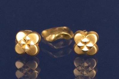 une paire de boucles d'oreilles en or sur un fond bleu avec des reflets