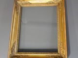 un cadre doré ancien avec un miroir accroché à un mur gris