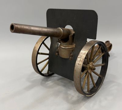 un vieux canon monté sur roues, avec une pancarte accrochée dessus