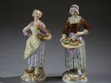 pair of figurines of a woman and a man with baskets of fruit