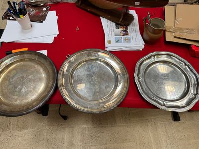 three silver plates on a table with a red table cloth