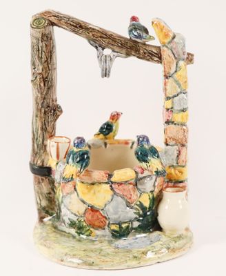 a ceramic water fountain with birds perched on a branch