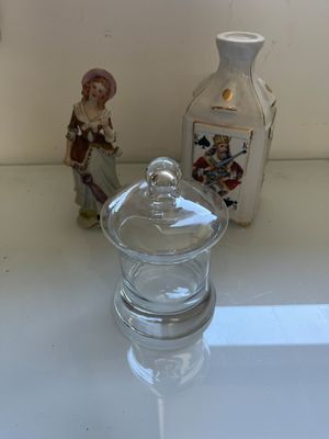 a small glass jar sitting on a counter next to a small glass bottle