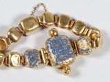 gold and blue beaded bracelet with gold accents on a white surface