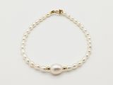 un gros plan d'un bracelet de perles blanches posé sur une surface blanche