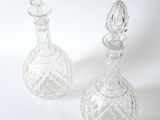 two clear glass bottles sitting next to each other on a white surface