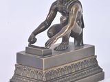 statue en bronze représentant un homme à genoux sur un socle surmonté d'une boîte