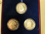 two silver coins in a purple box on a table next to a card