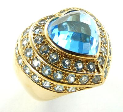 une image représentant une bague en or sertie d'une topaze bleue entourée de cristaux bleus et transparents