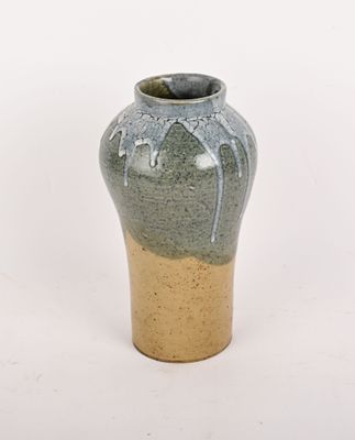 un vase vert avec un socle marron sur fond blanc