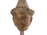 statue représentant la tête d'une personne coiffée d'un chapeau, posée sur un socle en bois