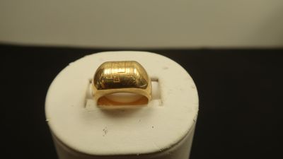 une photo d'une bague en or posée sur un socle blanc