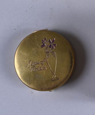 a small gold box with a purple flower on it