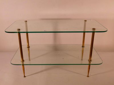 une table basse en verre et en laiton avec deux étagères