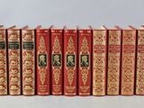 six red books lined up in a row on a white surface