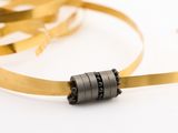 a gold ribbon and a black bead on a white surface