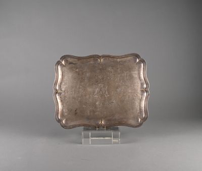 an antique silver plate on a clear stand on a gray background