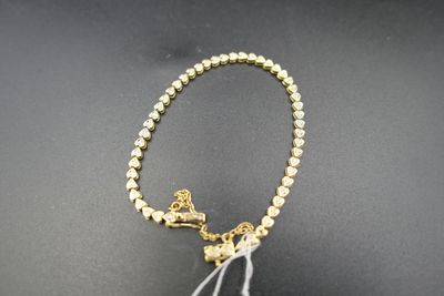 un gros plan sur un collier en perles dorées orné d'un pompon