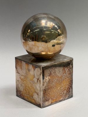 a metal ball sitting on top of a wooden block