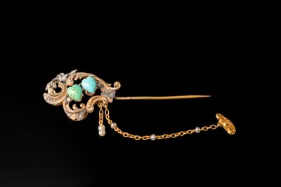 un gros plan d'une broche en or ornée d'une pierre turquoise