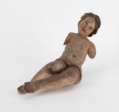 une vieille figurine en bois représentant un bébé allongé par terre