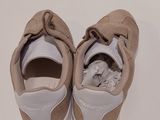 pair of beige and white shoes on a white surface with a white background