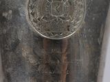 an old silver vase sitting on top of a table next to a white wall