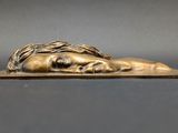 a bronze statue of a woman laying down on top of a book