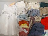 une boîte blanche remplie de vêtements et des vêtements posés sur une table