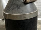 un bidon à lait noir et argent posé par terre