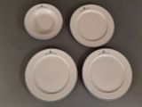 quatre assiettes blanches ornées de motifs verts sont disposées sur une surface grise