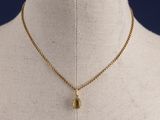 un collier en or avec un pendentif en forme de larme sur un mannequin