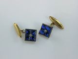 une paire de boutons de manchette bleus et dorés sur un fond blanc