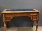 un vieux bureau en bois avec un plateau en verre, posé sur un parquet en bois massif