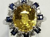 un gros plan d'une bague sertie d'un saphir jaune entouré de diamants bleus et blancs