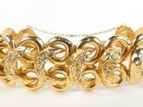 a close up of a gold bracelet on a white background