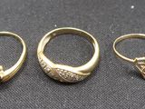 three gold rings and a diamond ring on a black cloth