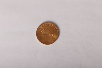 une petite pièce de monnaie posée sur une surface blanche, avec un fond blanc