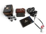 an image of a camera, a book, and a pair of ear buds are laid out on a white surface