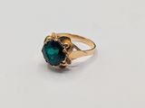a close up of a gold ring with a green stone