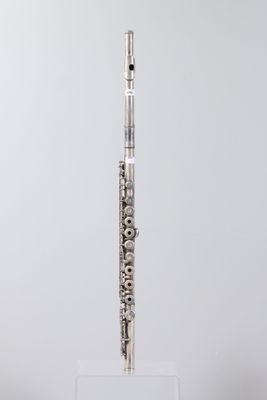a silver flute on a clear stand against a white background