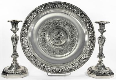 un plateau en argent et deux bougeoirs en argent posés sur une table