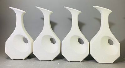 quatre vases blancs sont alignés sur une table