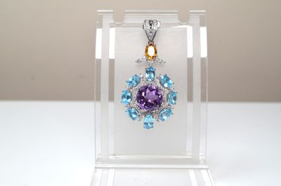un pendentif en cristal violet et bleu présenté dans un écrin transparent