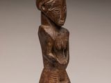 a wooden statue of a woman with a hat on her head