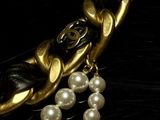 pearls and gold chains on a black table with a black background