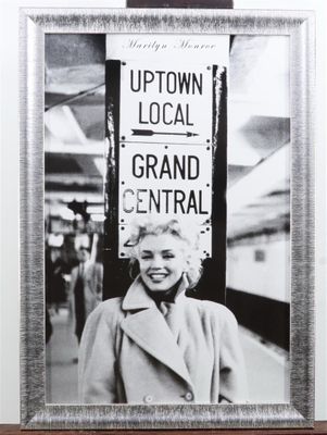 black and white photograph of a woman standing in front of a sign