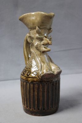 a small vase with a cat on top of it