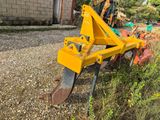 a yellow plow sitting on the ground next to a building